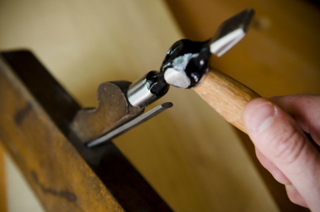 A Woodworker Using A Metal Peen Hammer To Set The Wedge On A Molding Plane