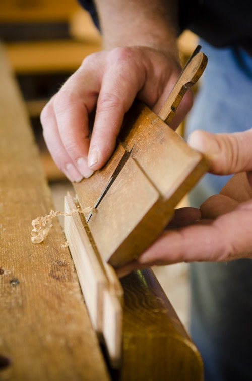 Woodworker Using A Round Hollow Molding Plane On A Door Frame With Woodworking Hand Tools