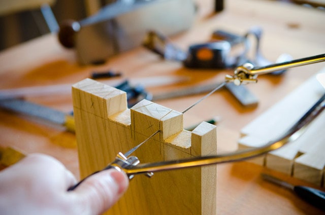 Coping Saw Cutting Dovetail Pins On Woodworking Workbench