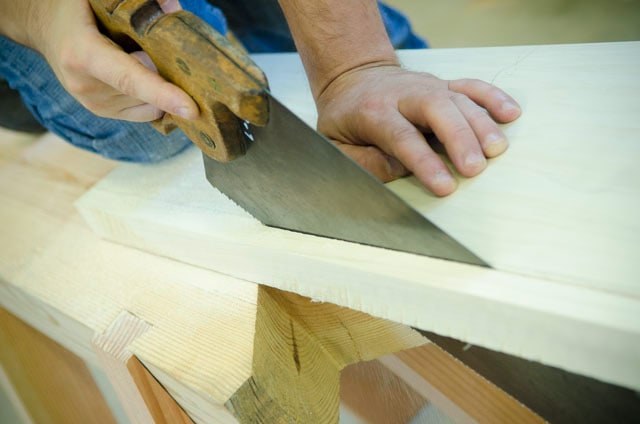 Travail du bois déchirant une planche avec une scie à main