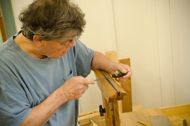 Un menuisier à l'aide d'outils d'affûtage de scie à main pour affûter les scies à main