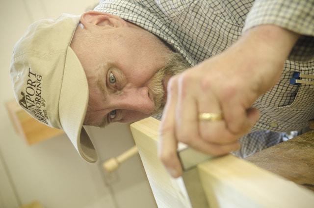 An Older Male Woodworking Student Checking A Board With A Try Square At A Woodworking Workbench