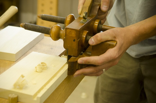 Closeup View Of An Antique Wooden Plow Plane Cutting A Groove In A Board