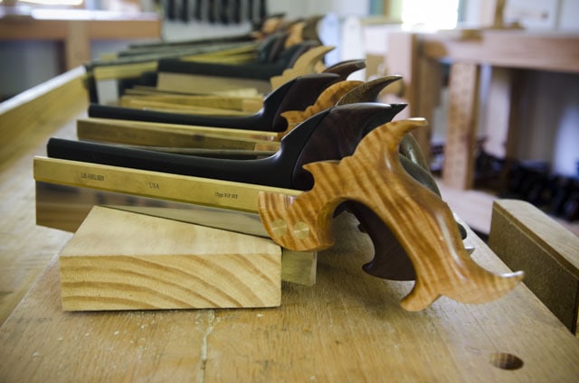 Row Of Dovetail Saws And Back Saws Sitting On A Woodworking Workbench