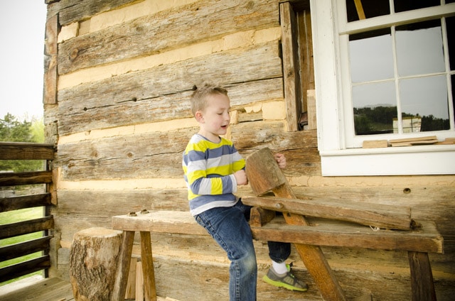 Little Boy Sitting On A Woodworking Shaving Horse At The Frontier Culture Museum