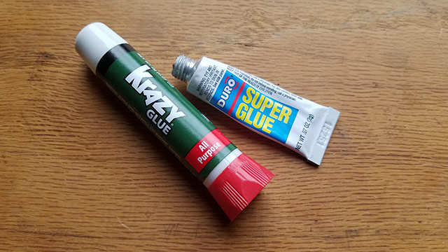 Krazy Glue And Super Glue Sitting On A Woodworking Workbench. Also Called Cyanoacrylate Glue