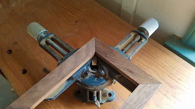 Picture Frame Clamp Or Miter Clamp Holding A Picture Frame Together On A Woodworking Workbench