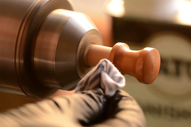 Woodturner Applying Danish Oil Finish To A Cherry Shaker Knob While Spinning On The Lathe