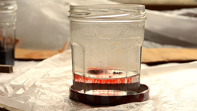 Mixing Aniline Dye In Jar With Red Streaks In The Water
