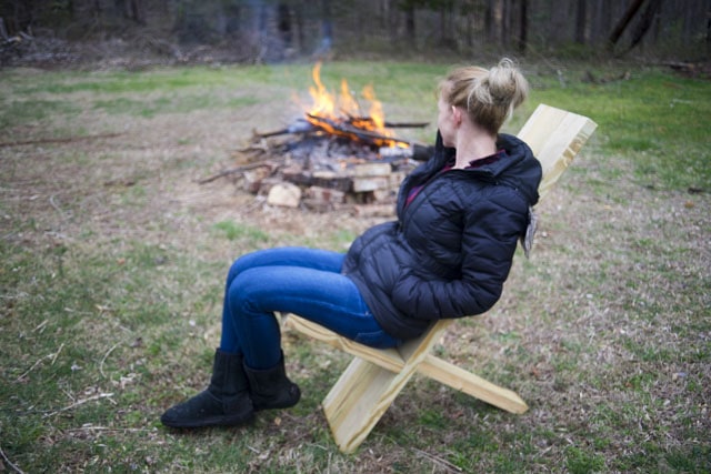 Beautiful Blond Woman Sitting On A Viking Camp Chair With A Camp Fire In The Background
