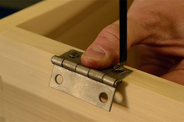Driving screws with a screw driver while Installing butt hinges on a dovetail chest