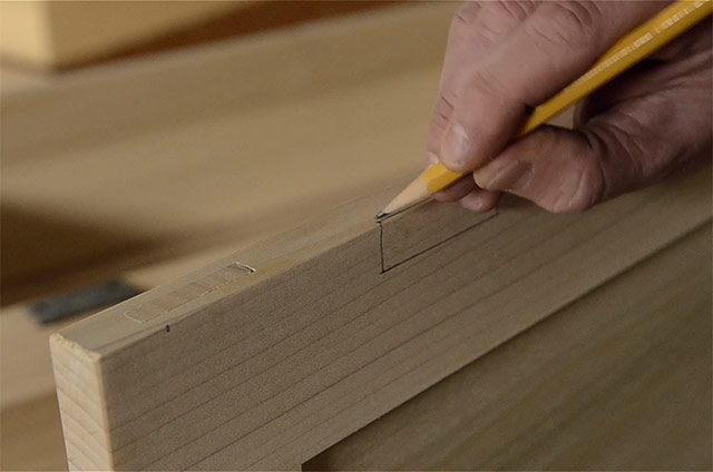 marking a mortise with a pencil while Installing butt hinges on the lid of a dovetail chest
