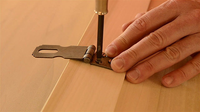 Woodworker Using A Screw Driver To Drive Slotted Wood Screws Into Historical Hasp Hardware Installed On A Dovetail Chest