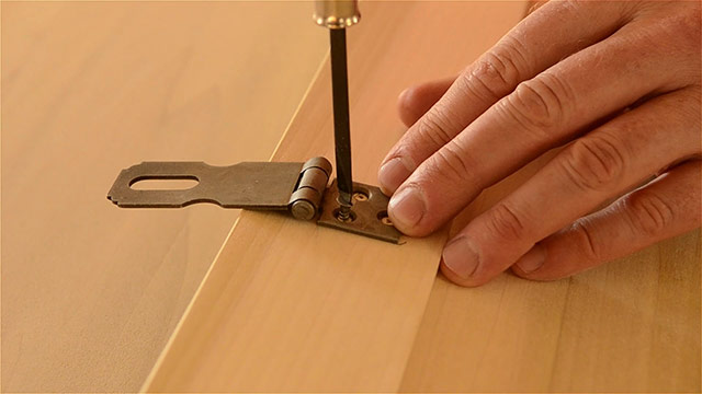 Woodworker Using A Screw Driver To Drive Slotted Wood Screws Into Historical Hasp Hardware Installed On A Dovetail Chest