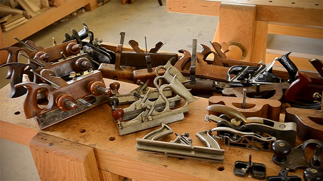 joinery planes on a moravian workbench, including plow planes, router planes, shoulder planes, and tongue and groove planes