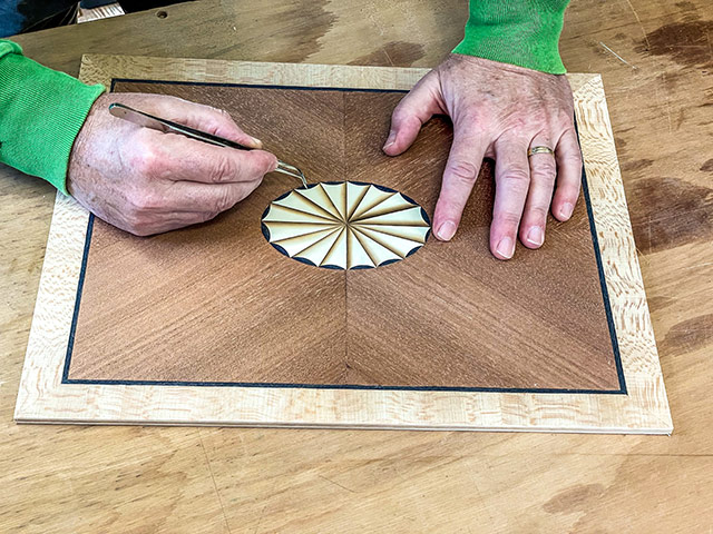 Dave Heller Placing Wood Veneer Pieces On A Furniture Panel With An Oval Fan