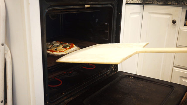 Using A Wooden Pizza Peel To Cook A Pizza In An Oven